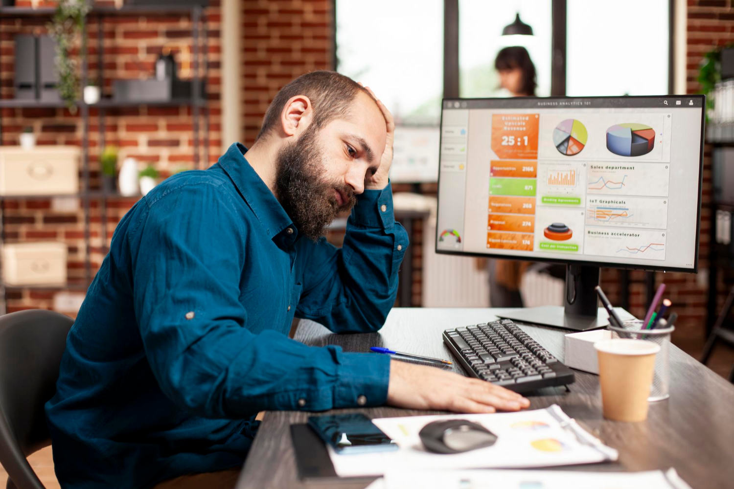 Frustrated man in front of a computer analyzing business analytics dashboard.
